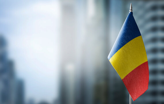 A small flag of Romania on the background of a blurred background
