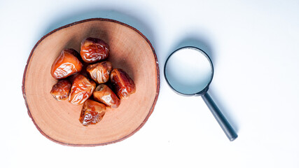 Kurma or dates fruits isolated with magnifiying glass on white background