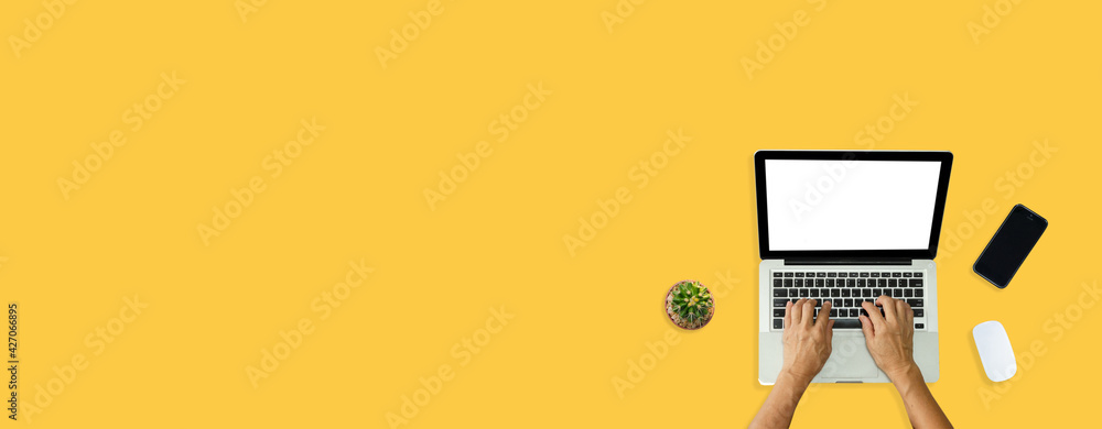 Poster hand using computer laptop and mouse, phone from above on yellow background.