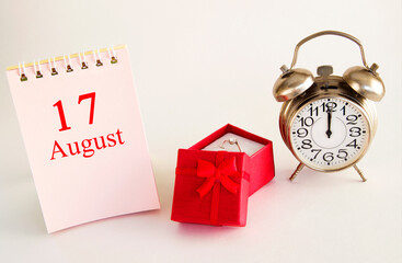 calendar date on light background with red gift box with ring and alarm clock with copy space.  August 17 is the seventeenth day of the month