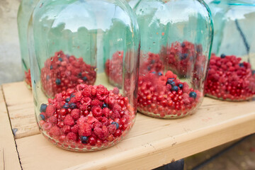 Unsealed glass jars with raspberries and currants, prepared for canning.