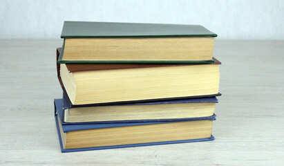 A stack of old books on a wooden table. Educational and entertainment books