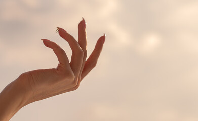 Beautiful female hand on the background of the sky