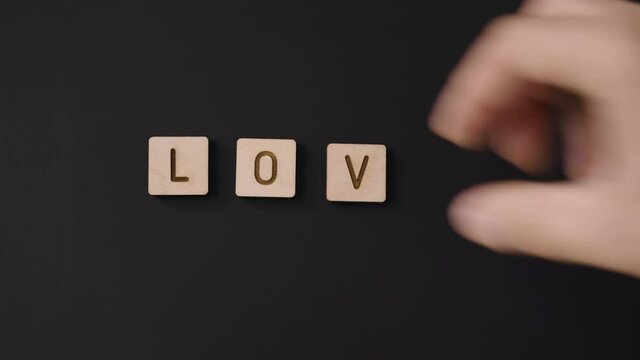 Male caucasian hand spells LOVE with letter pieces, high angle close up