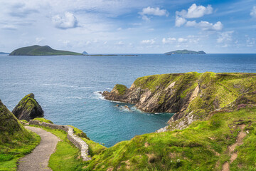 Path leading down to Dunquin Pier surrounded by turquoise water of Atlantic Ocean and tall cliffs, Dingle, Wild Atlantic Way, Kerry, Ireland