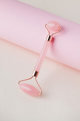 Face roller jade of pink color. Face care at home, alternative medicine. Copy space.