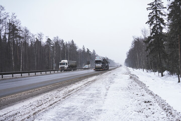 Trucks on the highway in dirty weather, Dangerous driving conditions in winter in cloudy weather.