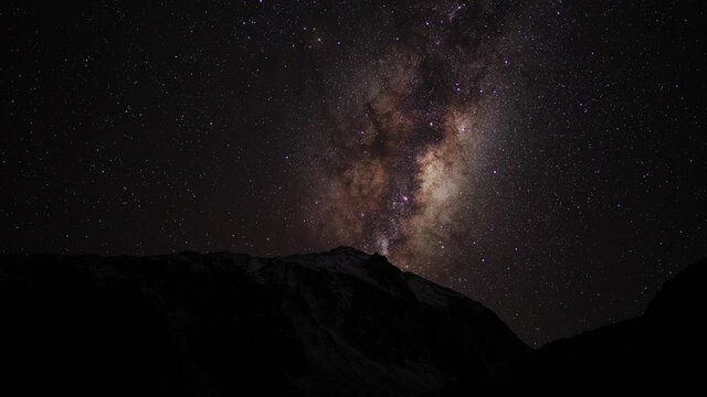 Amazing dark, clear, starry winter night skies and bright Milky Way light up snowy Mount Herman, South Island Alps of New Zealand