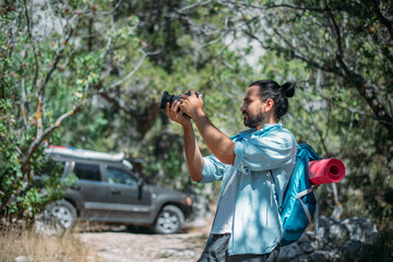Male photographer with a camera on a hike by car