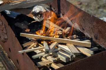 Firewood is burning in the grill. A fire breaks out in the grill. Dry firewood flares up.