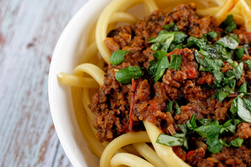 Close up of Italian pasta with bolognese, in a bowl. On rough gray wooden boards.