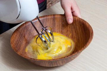 Beat the raw eggs in a bowl with a mixer. The cooking process. Selective focus.
