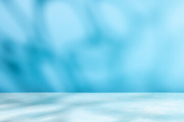Abstract shadow on table top and blue wall background. Blurred backdrop with copy space. - obrazy, fototapety, plakaty