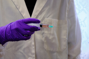 Hand with a latex glove holding a syringe with a covid 19 vaccine.