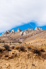 Looking up at jagged Rocky Mountain peaks under a blue sky with white cloud.
