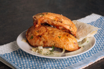 Delicious grilled chicken breasts on a plate on the dark background