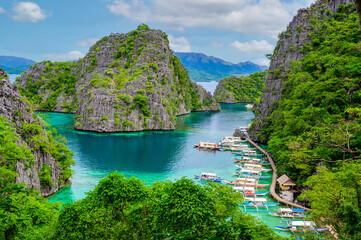 Blue crystal water in paradise Bay with boats on the wooden pier at Kayangan Lake in Coron island, Palawan, Philippines.
