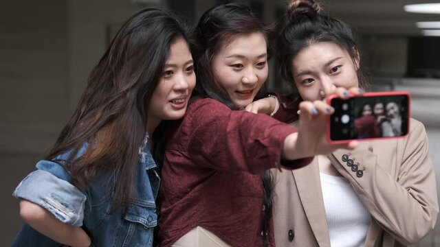 Portrait of a group of asian women friends taking a selfie with a mobile phone together.