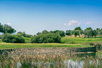 Golf course green with water hazard and stone wall