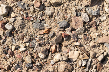 Różne małe kamienie leżące na piachu.