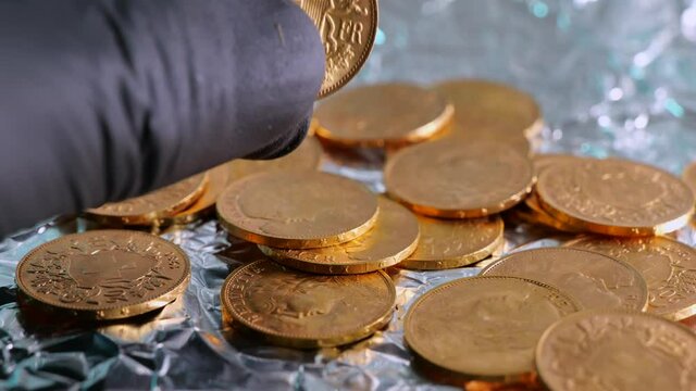 Hand with gloves checking shiny golden 20 swiss francs vreneli coins. Close up shot.