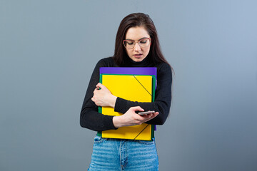 Obraz premium female with smartphone holding a colorfuls folders with documents, isolated on dark background