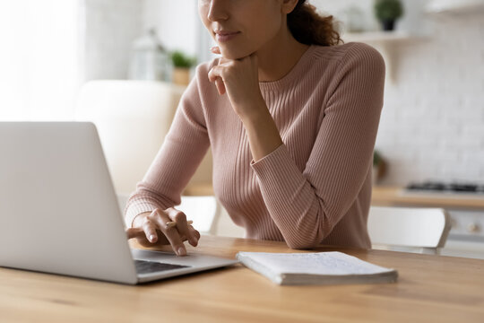 Close up of teen female student work on learning project online from home workplace surf web search information on laptop. Busy young woman freelancer think on report use web app to analyse e document
