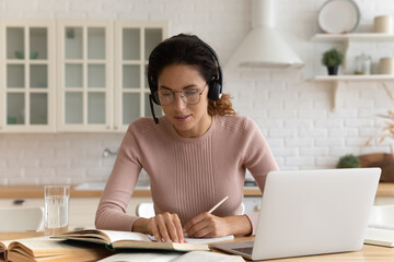 Thoughtful young woman work by computer in modern headset study literature do research take notes....