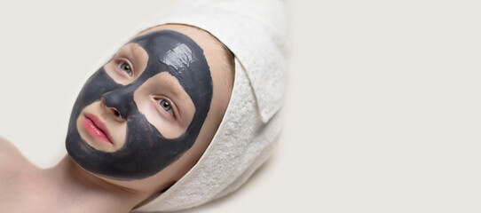Cleansing mask on the face. Girl with a charcoal mask.