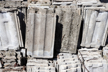 Piles of old gray concrete roof tiles. Building debris. Recycling roof tile waste material
