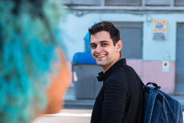 smiling young man waving to girl or friend on the street