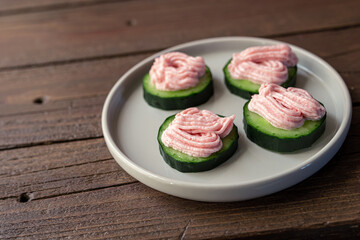 Toasts with cucumber and tarama on a gray plate on a dark wooden table, close-up