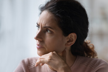 Run of bad luck. Close up of worried thoughtful young hispanic female face look aside prop chin...