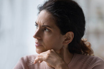 Run of bad luck. Close up of worried thoughtful young hispanic female face look aside prop chin with hand make hard decision. Nervous millennial woman with dark look think consider on serious problem