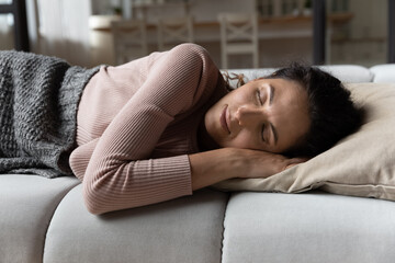 Sweet dreams. Tired young hispanic woman sleep on cozy sofa at home put both hands under head...