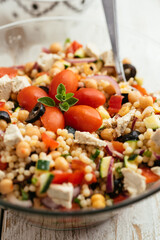 Home made mediterranean couscous salad with bell pepper, zucchini, tomatoes, chickpeas, olive and vegan feta