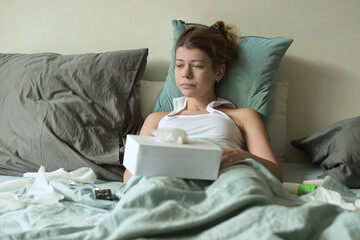 A young sick woman lies in bed, front view