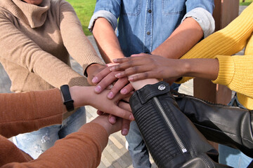 Hands of people of different nationalities are folded together as a symbol of unity and peace,...