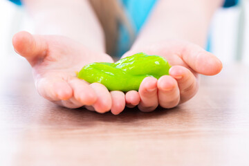 Yellow slime in the hands of a child. A small child is eating a slime. Play Slime Toy