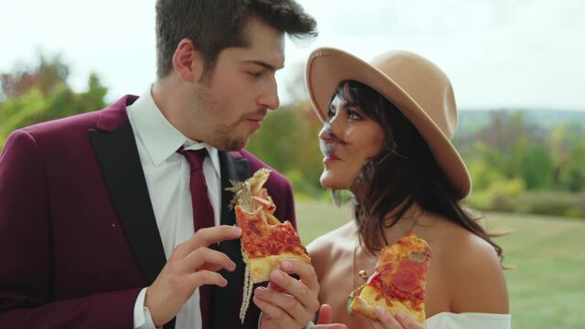 Fedora hat falls off boho bride eating pizza with groom, Slowmo Closeup