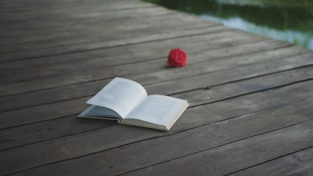 Backgound of open book lying on the wooden floor, wind moving pages