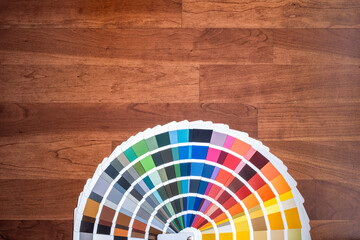 an open color swatch with all the different colors folded out on a wooden surface, cherry colored wood texture, horizontal