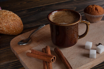 A cup of aromatic black coffee, grains of different varieties on the table. Morning espresso or Americano coffee for breakfast in a beautiful cup. Still life. Cinnamon sticks. 