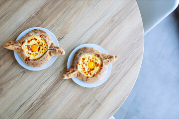 two delicious Adjarian khachapuri on a wooden background