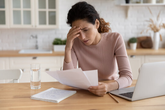 Worried stressed millennial female freelancer scratch forehead think on bank notification about business bankruptcy tax loan mortgage debt. Unhappy latin woman concern about bad news in paper letter