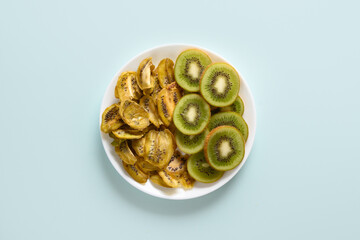 Sliced fresh and dried fruits kiwi chips on blue background, home drying. Snack vegan free sugar food. View from above.