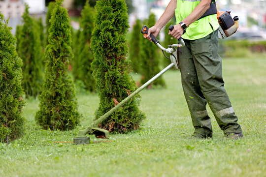 Man Gardener Worker Changing Landscape with String Lawn Trimmer