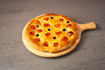 focaccia typical food of Puglia Italy. Focaccia on cutting board with mozzarella, tomatoes and olives.