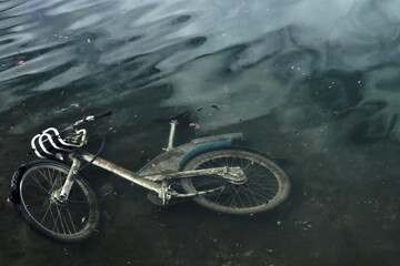 Dirty abandoned bike lying under the water.