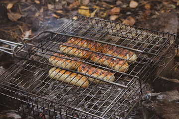 Grilled sausages on the grill. Barbecue meat. Roasted kebab. Grilled food. Smoked sausages outdoor. Fried cuisine. Camping concept. Delicious BBQ bratwurst. Idyllic picnic concept. Bonfire with grill.
